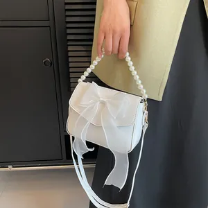 Detailed view of white lace bag featuring an organza bow and pearl handle beads