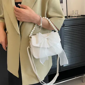 Detail of white lace bag with organza bow, pearl handle and slim crossbody strap