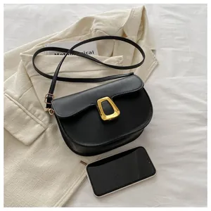 Top-down view of black matte saddle bag with gold metal buckle and smartphone for scale
