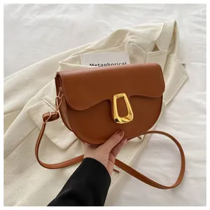 Detailed view of a brown semi-circular saddle bag with unique golden geometric metal clasp