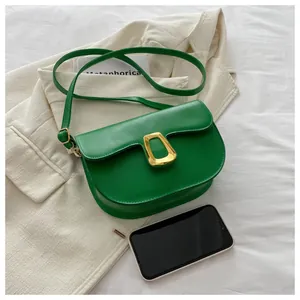 Green PU leather saddle bag detail with gold metal buckle and smartphone for size scale
