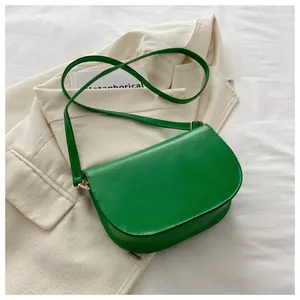 Close-up of bright green saddle bag on a cream blazer with golden metal hardware detail