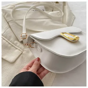 Detail of white saddle bag showing gold metal buckle and smooth faux leather texture