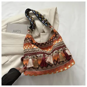 Detalle del bolso tejido bohemio con flecos largos y correa geométrica de colores vivos