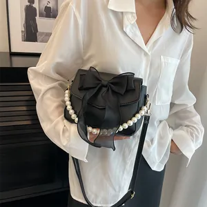 Detail of black lace bow handbag featuring pearl handle and matte synthetic leather finish