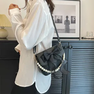 Detail of black bow shoulder bag with elegant white pearl trim for a stylish look