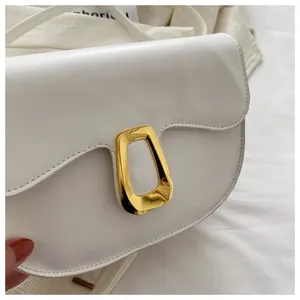 Close-up of white minimalist saddle bag with gold hardware and smooth leather texture