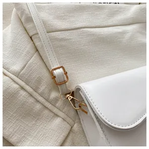 Detail of white PU saddle bag featuring polished gold metal hardware and detachable strap