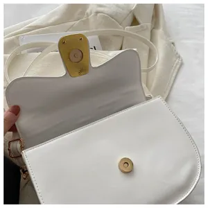 Close-up of white leather saddle bag showing magnetic gold buckle and fine stitching