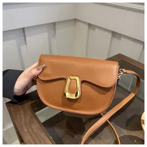 Detail view of caramel brown saddle bag featuring a textured finish and golden buckle