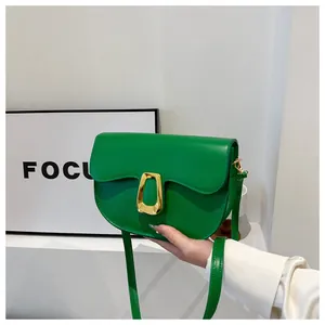 Close-up of a green saddle bag featuring a wavy flap and gold trapezoid metal buckle