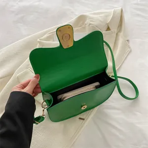 Minimalist green saddle shoulder bag showing interior space for phone and wallet