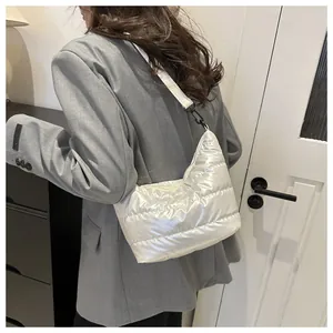 Vista dettagliata di una borsa a tracolla trapuntata bianca indossata con un blazer grigio