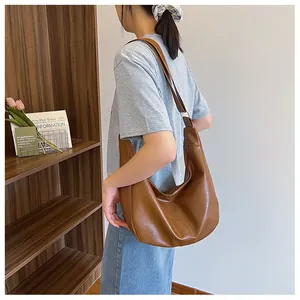 Detail of caramel leather hobo bag showing supple texture and wide shoulder strap