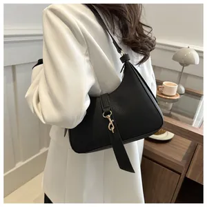 Seitenansicht der schwarzen Achseltasche aus genarbtem Leder mit goldener Metallschnalle