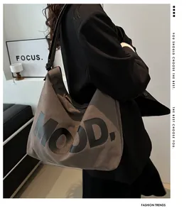 Detailed close-up of brown canvas tote bag with black MOOD lettering and wide strap