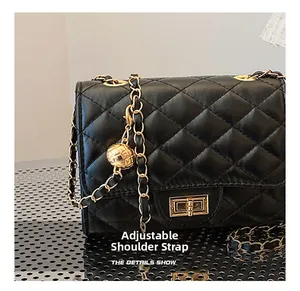 Detail of adjustable gold ball chain strap on black quilted leather crossbody bag