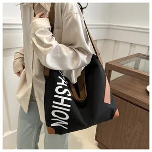 Fashion canvas tote bag with black body and brown straps shown on a model in a natural setting