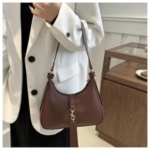 Makroaufnahme von dunkelbraunem Leder mit Lychee-Narbe und goldenem Metallhaken an der Tasche