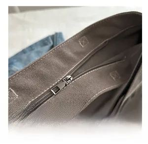 Detail of the smooth metal zipper and stitching on the brown canvas tote bag