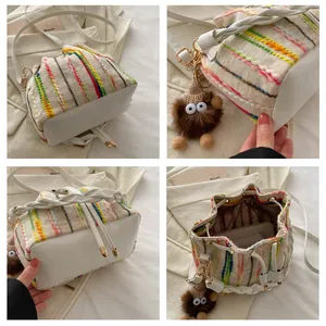 Detailed view of colorful woven bucket bag with leather base and plush charm accessory
