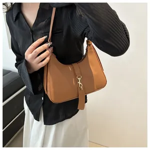 Detailaufnahme von braunem Leder mit Lychee-Muster und goldener Schnalle an der Schultertasche