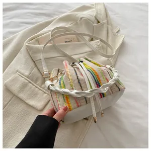 Detailed close-up of woven vertical stripes bucket bag with leather base and gold hardware