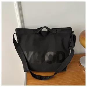 Detail of black canvas tote bag showing the MOOD letter print and wide strap hardware
