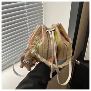 Detail of woven bucket bag with colorful vertical stripes and cute plush monster charm