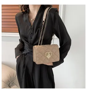 Détail d'un sac matelassé abricot avec fermoir cœur doré et bandoulière en chaîne