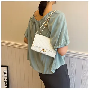 Detail of white quilted crossbody bag with gold chain strap and metal ball decor