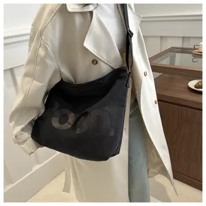 Detail of black canvas tote bag showing shiny black FOOD. letter print and adjustable strap