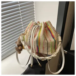 Detail of vertical striped bucket bag with drawstring closure and plush monkey charm