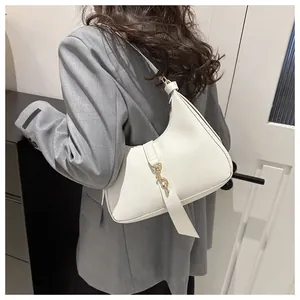 Detail der weißen Hobo-Tasche mit goldenem Kolbenverschluss an der Schulter