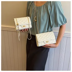 Detail view of two white quilted chain bags with gold hardware and ball charms on a model