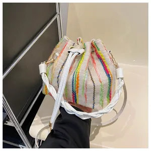 Close-up of beige bucket bag with colorful embroidered stripes and woven strap detail