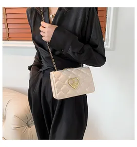 Détail d'un sac à bandoulière matelassé blanc avec fermoir en métal doré en forme de cœur