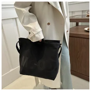 Close-up of black canvas tote bag with MOOD lettering and dual carry straps