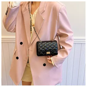 Detail of black quilted leather shoulder bag with gold chain strap on pink blazer