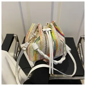 Close-up of beige woven bucket bag with vertical colorful embroidery and gold hardware