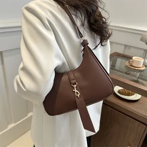 Braune Hobo-Schultertasche aus genarbtem Leder mit goldener Schnalle an einem Model