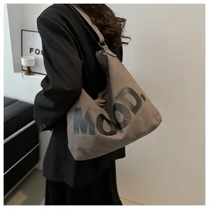 Detail of grey canvas shoulder bag with MOOD lettering in a minimalist urban setting