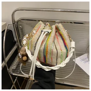 Close-up of beige knitted bucket bag featuring colorful vertical stripes and a cute charm