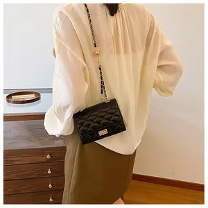 Close-up of black quilted crossbody bag with gold chain strap and metal ball charms