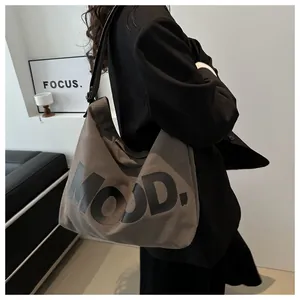 Detail view of large brown canvas crossbody bag with MOOD text on fashion model