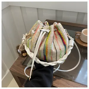Detail of canvas bucket bag with colorful vertical stripes and plush monster charm