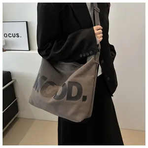 Close-up of brown canvas tote bag with bold MOOD letter print and wide strap