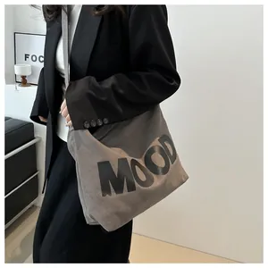 Detail of dark grey canvas tote bag with MOOD lettering worn as a crossbody bag