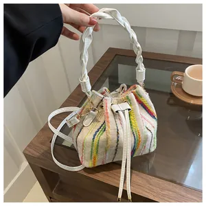 Detail of colorful striped woven bucket bag featuring white braided handle and gold hardware