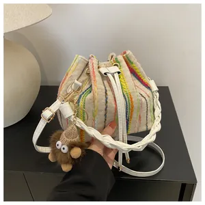 Detail of canvas bucket bag with colorful vertical stripes and cute monster pendant